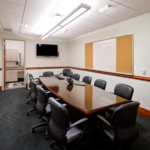 Private conference room with an elongated table and black chairs tucked in. 