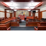 Inside a courtroom with redwood short rail separating the audience from the court official area.