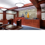Interior of a courtroom with two podiums facing the judge stand and the Great Seal of New Mexico on the all.