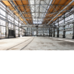 Interior view of the old train hanger with light shining through old and broken windows. 
