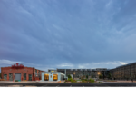 The newly renovated white building stands in front of the old red brick train hanger building. 