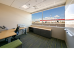 Interior office with a desk and chair sitting in front of a large window. 