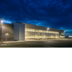 Exterior view of the Chevron Field Office with rows of windows with interior lights on. 