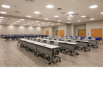 Four rows of desks neatly lined up with grey chairs tucked in under the desks. 