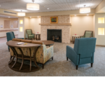 Living area with a floral print love seat and two teal single seats facing a fireplace. 