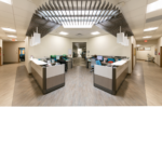 Nurse receptionist area with blue chairs and white walls and gray flooring. 