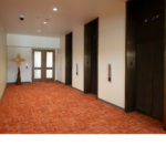 Room with elevator doors and orange carpet in the State of NM TIWA Building